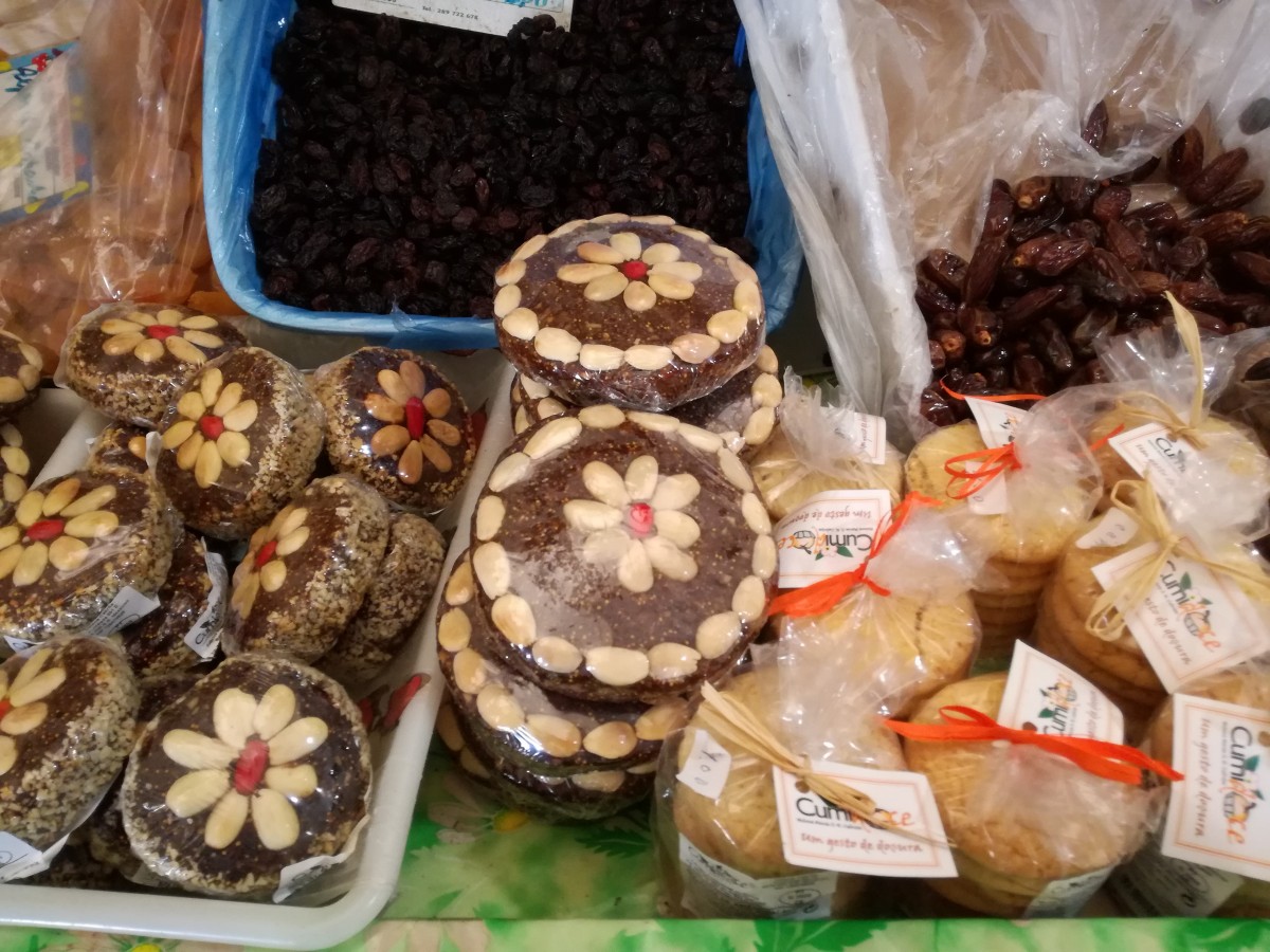 Platte, ronde vijgenkoeken, mooi versierd met amandelen in bloemvorm op de markt. Ernaast liggen rozijnen, dadels en amandelkoeken.