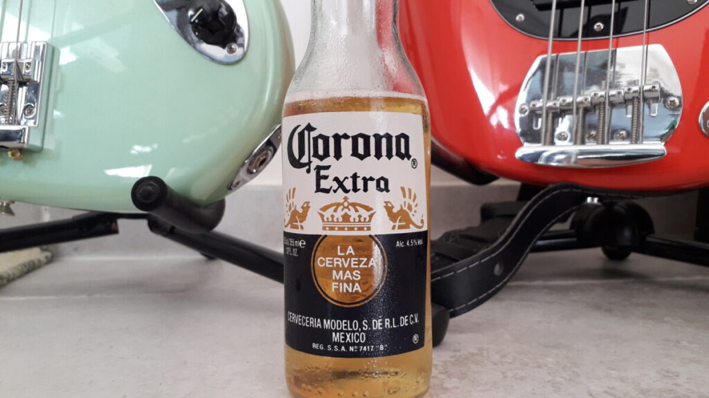 Fles corona bier met twee basgitaren op de achtergrond