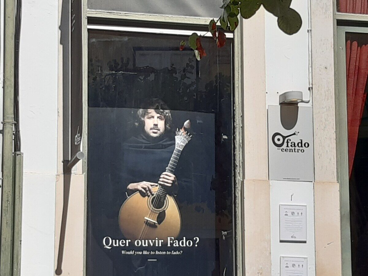 Poster van een fado gitarist achter een raam in Lissabon