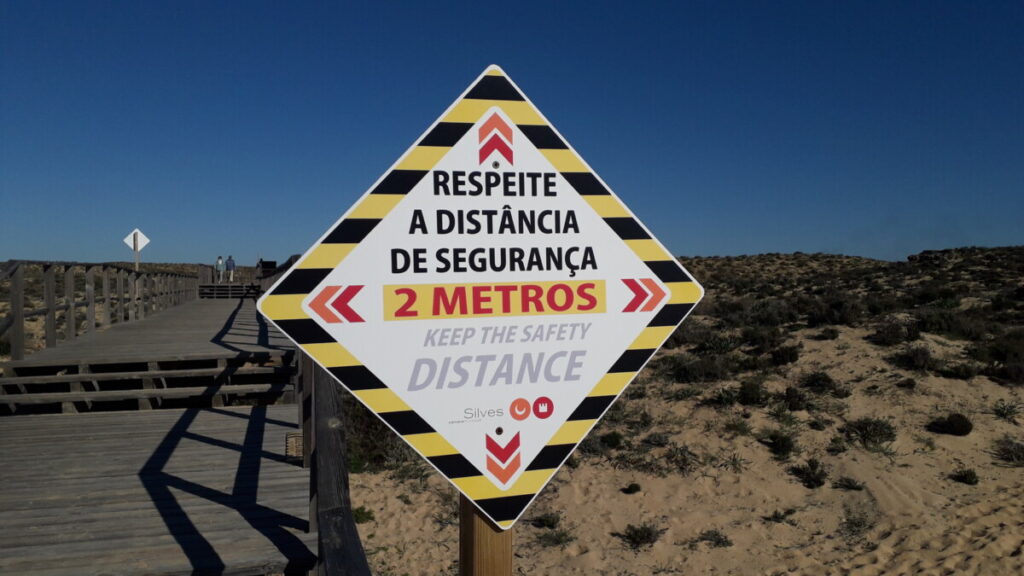 Verkeersbord bij duinovergang in de algarve in portgal, wat aangeeft dat er 2 meter afstand moet worden gehouden.