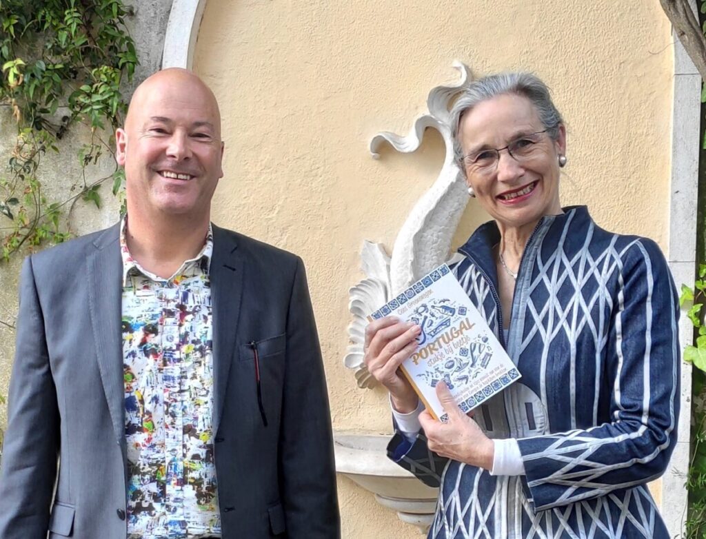 Ambassadeur Nienke Trooster en auteur Cees Groenewegen met het boek "Portugal, stukje bij beetje" in de tuin van de ambassadeursresidentie in Lissabon 