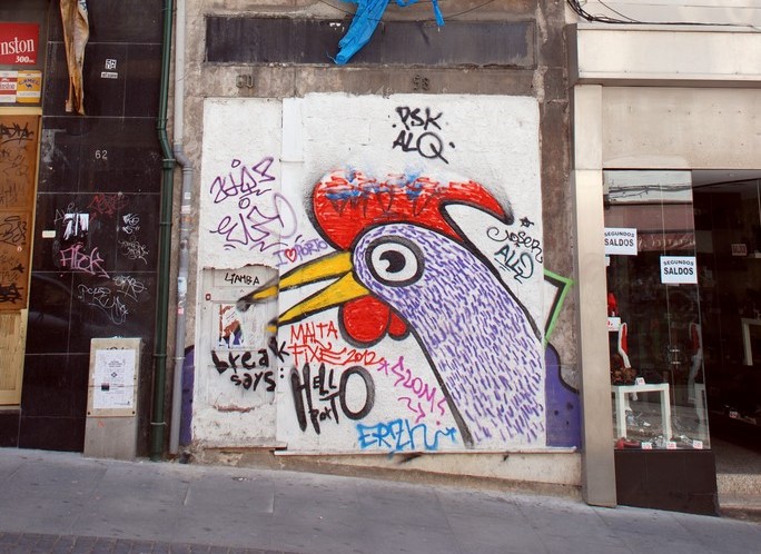 Haan van Barcelos in graffiti op een dichtgespijkerd winkelraam.