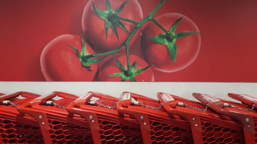 Muurschildering van tomaten met een rij rode winkelwagentjes / winkelkarretjes eronder, in Portugal. 