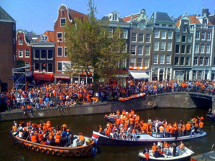 Boten vol oranje geklede mensen in de Amsterdamse grachten op koningsdag /koninginnedag