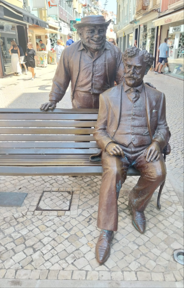 Sculptuur Zé Povinho en zijn geestelijke vader in de Rua das Montras in Caldas