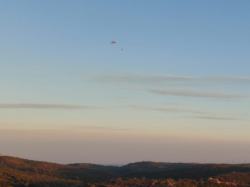 Helicopter met waterzak eronder boven het Portugese berglandschap.