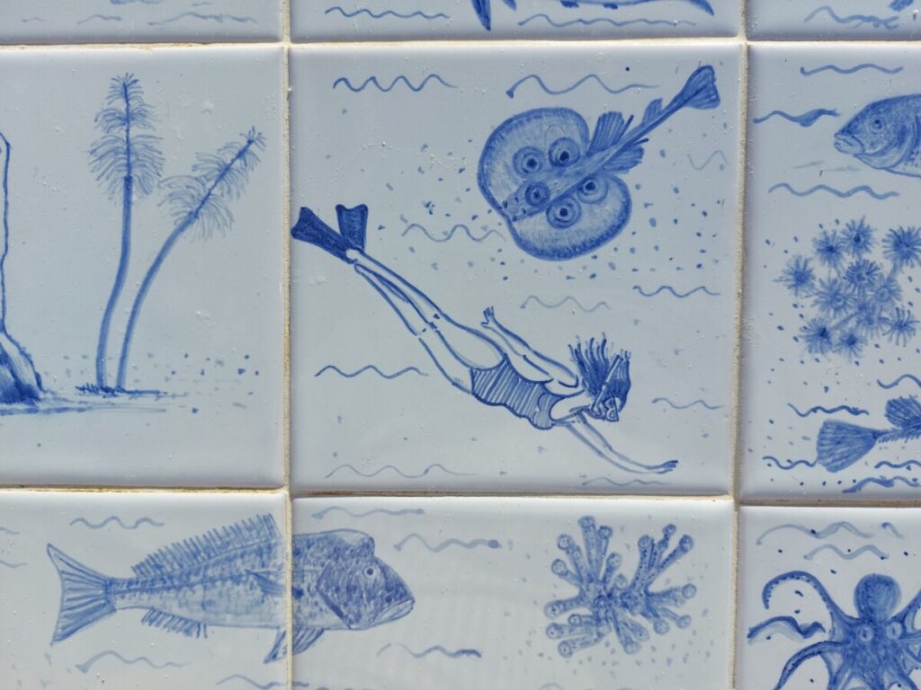 Portugese azulejos met tussen de vissen een snorkelaarster. 