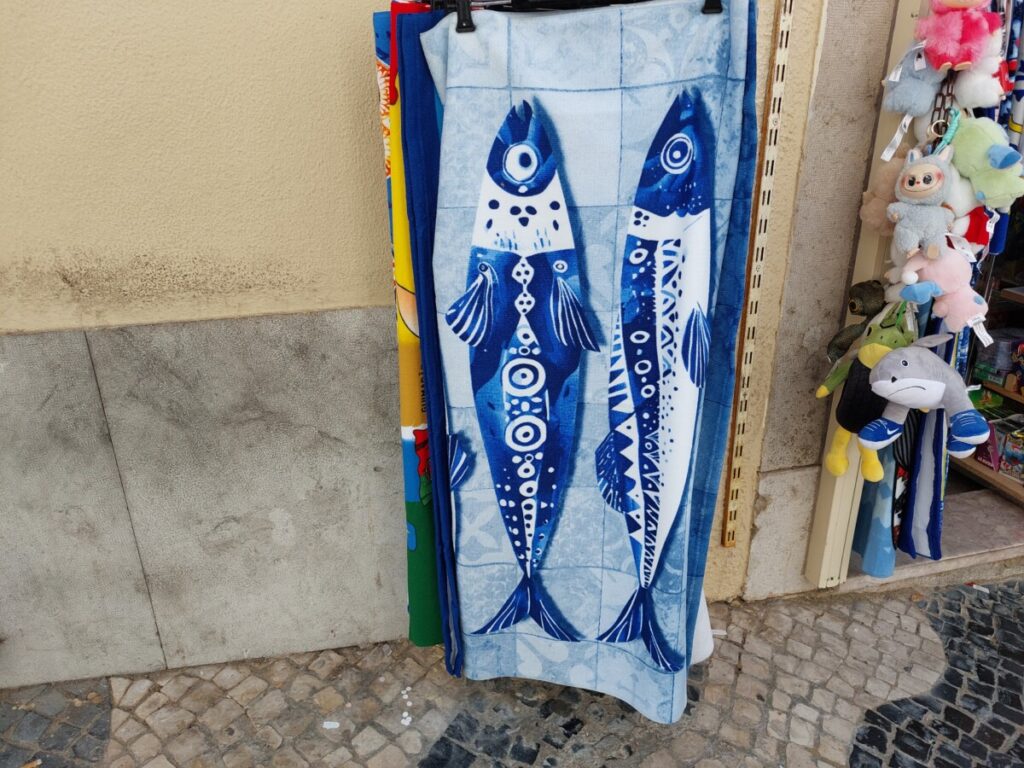 Blauwe handdoek aan een verkooprek met twee vissen erop en zonder tekst.