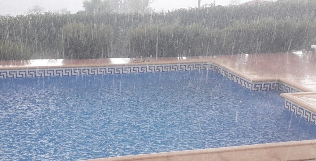 Regen plenst in een zwembad.