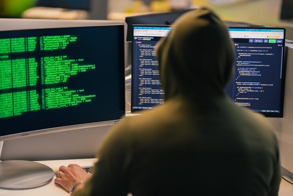 Man met hoodie aan computerschermen