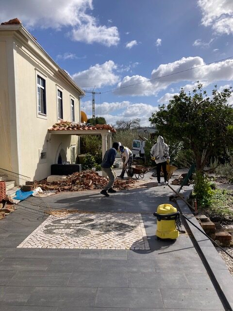 Drie mannen ruimen puin rond het huis