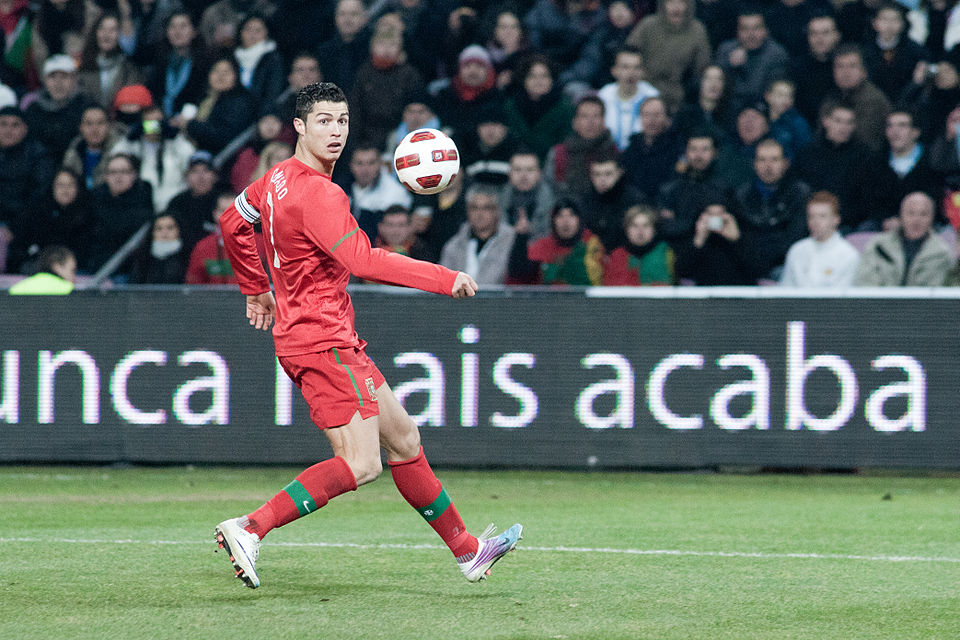 Cristiano Ronaldo in de kleuren van het Portugese nationale voetbalelftal, neemt een bal aan
