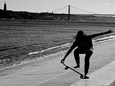 Skater met op de achtergrond de Ponte 25 de Abril en het standbeeld Cristo Rei, in Lissabon.