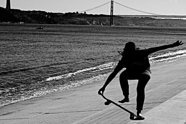 Skater met op de achtergrond de Ponte 25 de Abril en het standbeeld Cristo Rei, in Lissabon.