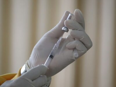 een vaccinatienaald wordt gevuld vanuit een buisje Foto Mufid Manjun voor Unsplash.