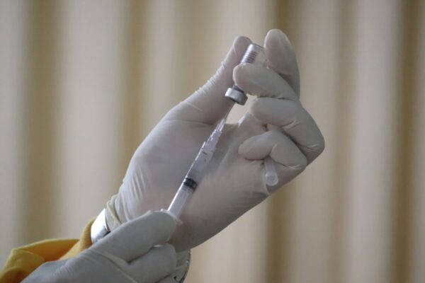 een vaccinatienaald wordt gevuld vanuit een buisje Foto Mufid Manjun voor Unsplash.